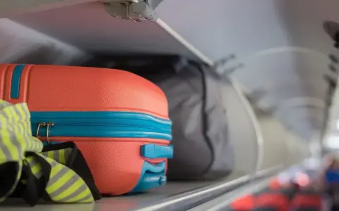 Pomarańczowa walizka i szara torba jako flydubai bagaż podręczny w schowku nad siedzeniami.