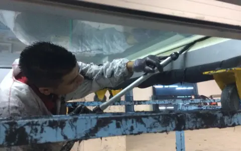 Un trabajador aplica **silicona estructural** en una junta de ventana.