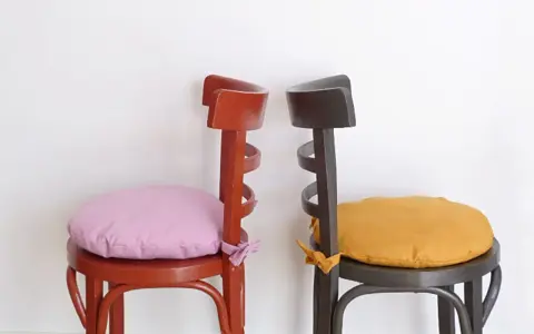 Dos sillas de madera pintadas, una roja con cojín lila y otra gris con cojín ocre. ¡Ideas para pintar sillas de madera!