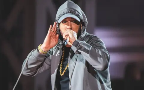 Eminem w kapturze i czapce, z mikrofonem w dłoni, jakby szykował kolejny eminem diss. Złoty łańcuch błyszczy.
