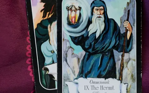 El tarot del mundo ermitaño: un sabio anciano con barba blanca ilumina el camino con una linterna, guiando en la introspección.
