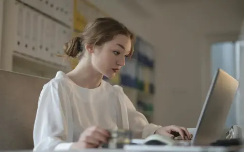 Młoda kobieta uczy się, jak zostać księgowym bez studiów, korzystając z laptopa i karty.