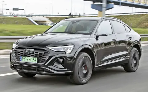 Czarny Audi Q8 e-tron sunie po drodze. Zastanawiasz się nad audi q8 cena? Ten luksusowy SUV coupe robi wrażenie.