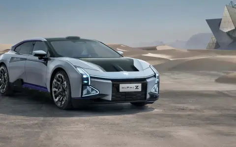 Futuristisches Elektroauto HiPhi Z in silber mit lila Akzenten, steht in einer Wüstenlandschaft vor einer modernen Glasarchitektur.