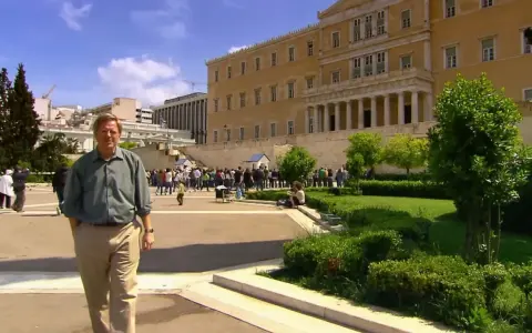Rick Steves explores Athens, standing before the Hellenic Parliament building with a crowd gathered for the changing of the guard.