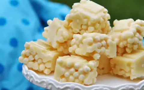 Leckere zuckerfrei leben rezepte: weiße Schokoladenstücke mit knusprigen Reispops auf einem weißen Teller.