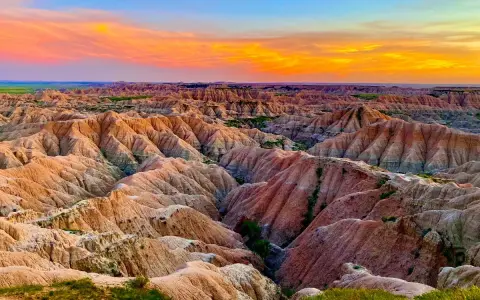 Un paisaje desértico con formaciones rocosas erosionadas, **las carcavas**, bajo un cielo anaranjado y azul al atardecer.