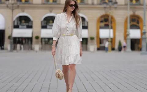 Sommerliches Outfit für eine Gartenparty: Weißes Lochstick-Kleid, goldener Gürtel, Sandalen und eine kleine Umhängetasche.