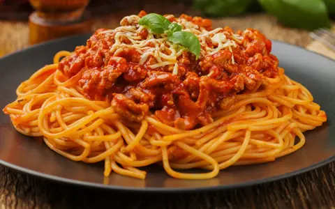 Pyszne spaghetti bolognese z mielonym mięsem, polane sosem pomidorowym i posypane serem. Idealne pytanie: jakie mięso do spaghetti?