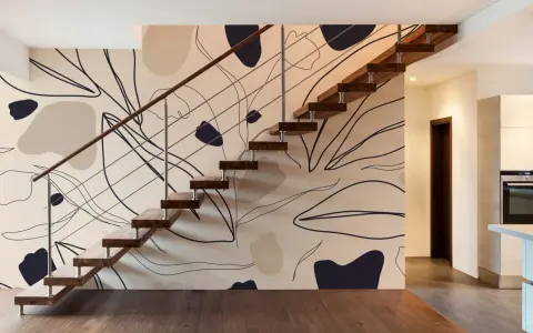 El papel pintado en las paredes de esta casa moderna presenta un diseño abstracto de hojas y formas orgánicas en tonos tierra, complementando la escalera flotante de madera.