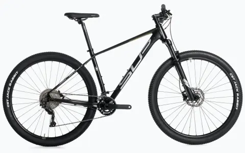 Czarny rower górski, idealny do wyścigów mtb xc. Wyposażony w amortyzator, przerzutki i opony CST Jack Rabbit.