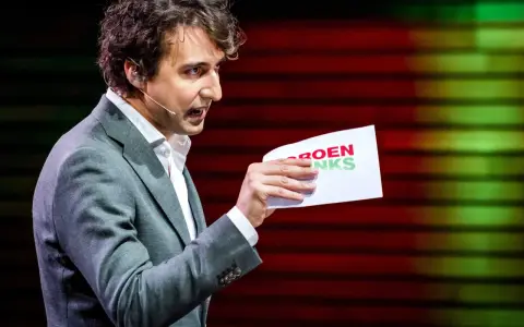 Man met krullend haar, in grijs pak, houdt een papier met "GROENLINKS" vast. Discussie over de Moslimbroederschap?