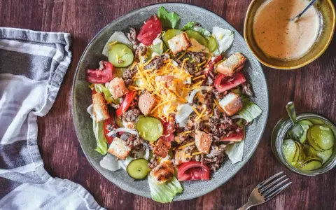 Ein Big Mac Salat mit Hackfleisch, Käse, Tomaten, Gurken und Croutons. Dazu eine cremige Sauce und eingelegte Gurken.