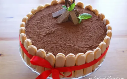 Elegancki tort whisky, udekorowany biszkoptami, kakao i miętą. Czerwona wstążka dodaje mu uroku.