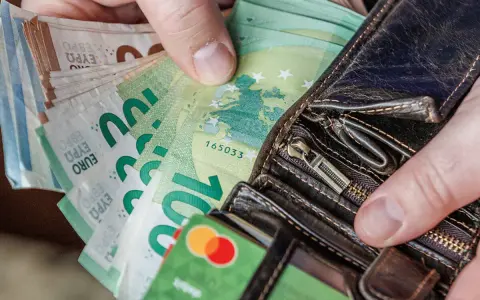 Ręce trzymające euro banknoty i karty płatnicze. Odpowiedź na pytanie: jaka waluta na Litwie? Euro.