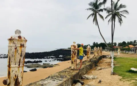 Kobieta przytula zardzewiały słup na plaży, wspominając dawne czasy na Wyspach Tomasza.