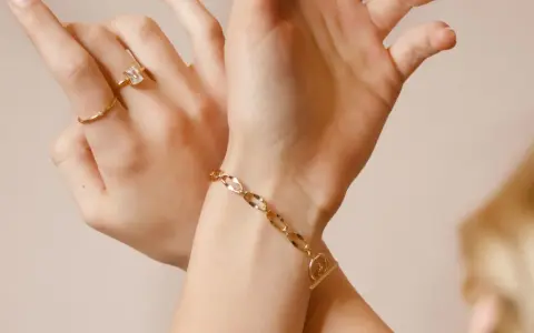 Mani adornate con anelli e un bracciale in metallo che sembra oro, un tocco di eleganza discreta.