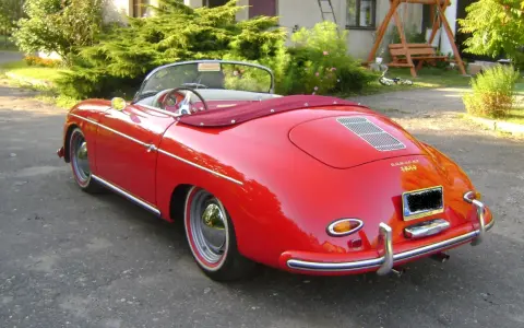 Czerwony kabriolet Porsche 356 z lat 50. stoi na podjeździe, gotowy na letnią przejażdżkę.