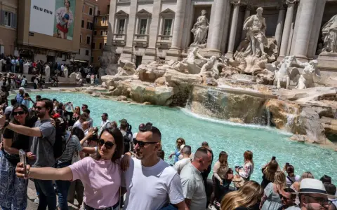 Foule de touristes admirant la fontaine de Trevi, la fontaine de l'amour à Rome, prenant des selfies devant les statues majestueuses et l'eau turquoise.