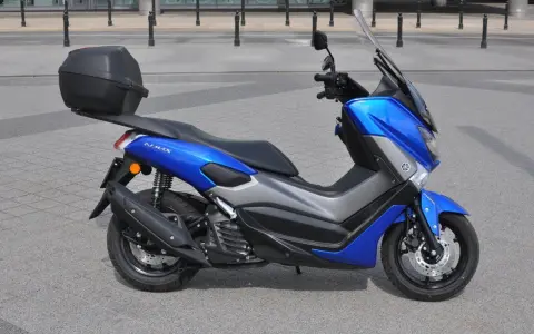 Niebieski skuter Yamaha NMAX 125 z kufrem, gotowy do jazdy. Jego prędkość maksymalna pozwoli na szybkie przemieszczanie się po mieście.
