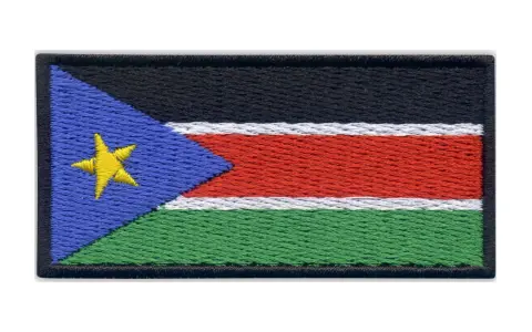 Naszywka z flagą Sudanu Południowego. Czarny pas na górze, pod nim biały, czerwony i zielony pas. Z lewej strony niebieski trójkąt z żółtą gwiazdą.