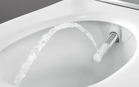 Chorro de agua saliendo de un inodoro moderno, mostrando la función de ducha integrada. Es como si el inodoro tuviera su propio bidet para quitar impurezas.