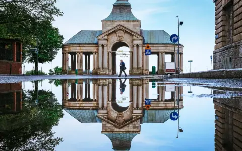 Odbicie zabytkowej budowli w kałuży, tworzące surrealistyczny widok. Nietypowe atrakcje Szczecin w deszczowy dzień.
