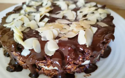 Pyszne ciasto z płatków owsianych, polane błyszczącą czekoladą i posypane płatkami migdałów.