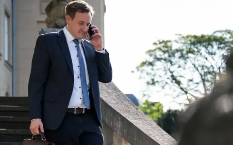 Anwalt am Telefon, der überlegt, wie kann ich mich schnell scheiden lassen. Er trägt einen dunklen Anzug und hält eine Aktentasche.