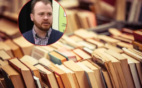 Mężczyzna z brodą w okręgu, na tle stosów książek. Może to być kadr z filmu "Wszystko co dobre", gdzie wiedza jest na wyciągnięcie ręki.