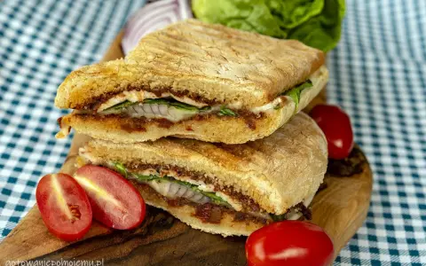 Pyszne panini z kurczakiem, suszonymi pomidorami i serem, podane z pomidorkami koktajlowymi i sałatą.