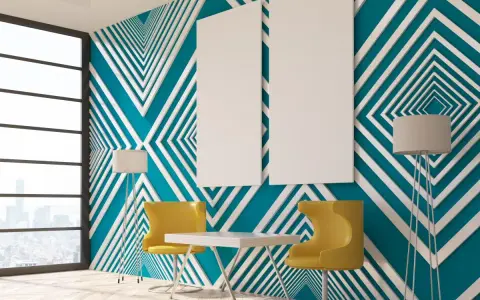 Modern room with striking **diseños pared geometrica** in teal and white. Two yellow chairs and a table sit before the wall, with floor lamps and blank canvases.