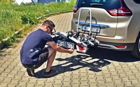 Mężczyzna montuje tablicę rejestracyjną na bagażniku rowerowym, by uniknąć mandatu za brak tablicy rejestracyjnej na bagażniku rowerowym.