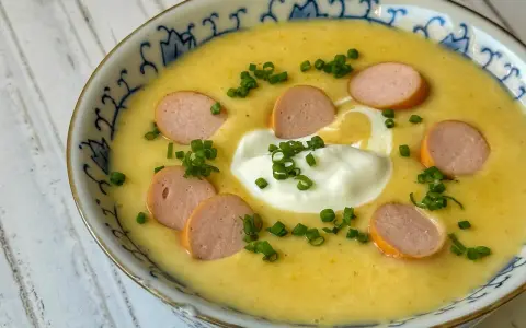 Cremige Kartoffelsuppe mit Würstchenscheiben, einem Klecks Sahne und Schnittlauch. Ein einfaches und leckeres Kartoffelsuppe Rezept für kalte Tage.