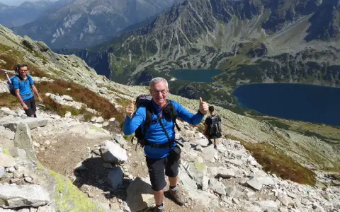 Trasa na Kozi Wierch. Dwóch turystów z plecakami na skalistym szlaku, w tle piękne tatrzańskie jeziora.