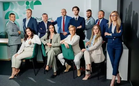 Zespół prawników w garniturach pozuje do zdjęcia w nowoczesnym biurze.