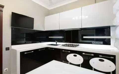Elegantes cocinas en blanco y negro, con encimeras blancas, gabinetes negros brillantes y detalles modernos.