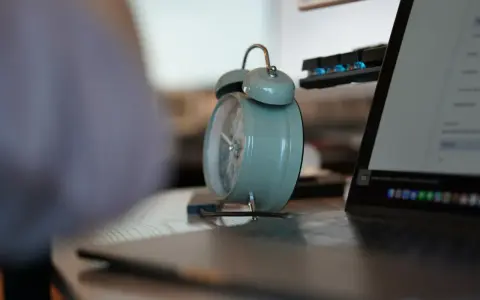 Budzik obok laptopa i klawiatury. Czas na pracę na 3/4 etatu.