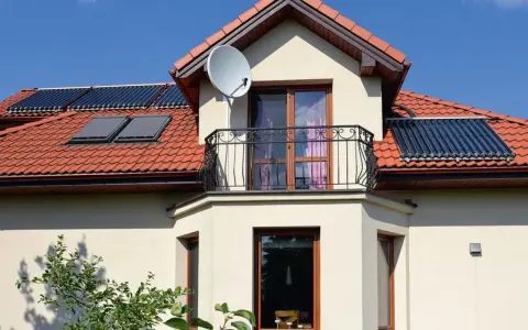 Elegancki wykusz w domu z balkonem i oknami, na dachu panele słoneczne.