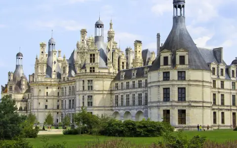 Le château de Chambord, chef-d'œuvre de la Renaissance, se dresse majestueusement sous un ciel bleu. Ses tours et cheminées sculptées rappellent une époque de splendeur.