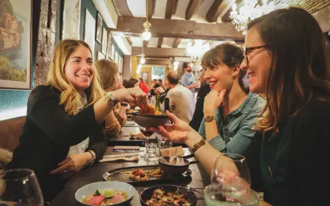 Amies joyeuses partageant des tapas dans un resto ouvert le dimanche à Rennes. Ambiance chaleureuse et conviviale.
