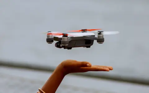 Kleine Drohne schwebt über einer Hand. Perfekt für den Einstieg, da sie die Drohne unter 250g Regeln erfüllt.
