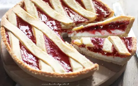 Una deliziosa crostata ricotta e marmellata, con una fetta tagliata per mostrare il ripieno cremoso e la crosta dorata.