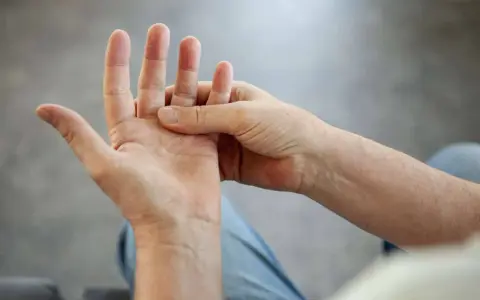 Eine Hand massiert die andere, um **Schmerzen in der Hand** zu lindern.