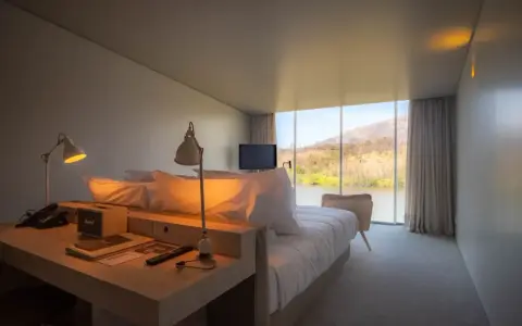 Un angolo studio in camera da letto con vista sul lago. Due lampade illuminano la scrivania con telefono e altoparlante.
