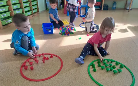 Dzieci w przedszkolu bawią się klockami, tworząc wzory w obręczach. To świetne zabawy dla 3 latka w przedszkolu.