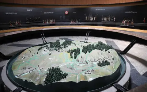 Model terenu przedstawiający bitwę pod Racławicami. Na tle miniatury żołnierzyków w historycznych strojach.