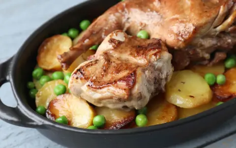Coniglio arrosto in padella con patate e piselli, un piatto succulento e invitante.