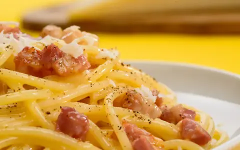 Pyszne spaghetti carbonara z kawałkami boczku i posypką. Szukasz, czym zastąpić parmezan?