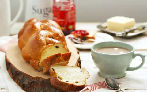 Pyszne, złociste ciasto drożdżowe, pokrojone w plastry, z dżemem, masłem i kawą. Idealne na śniadanie.
